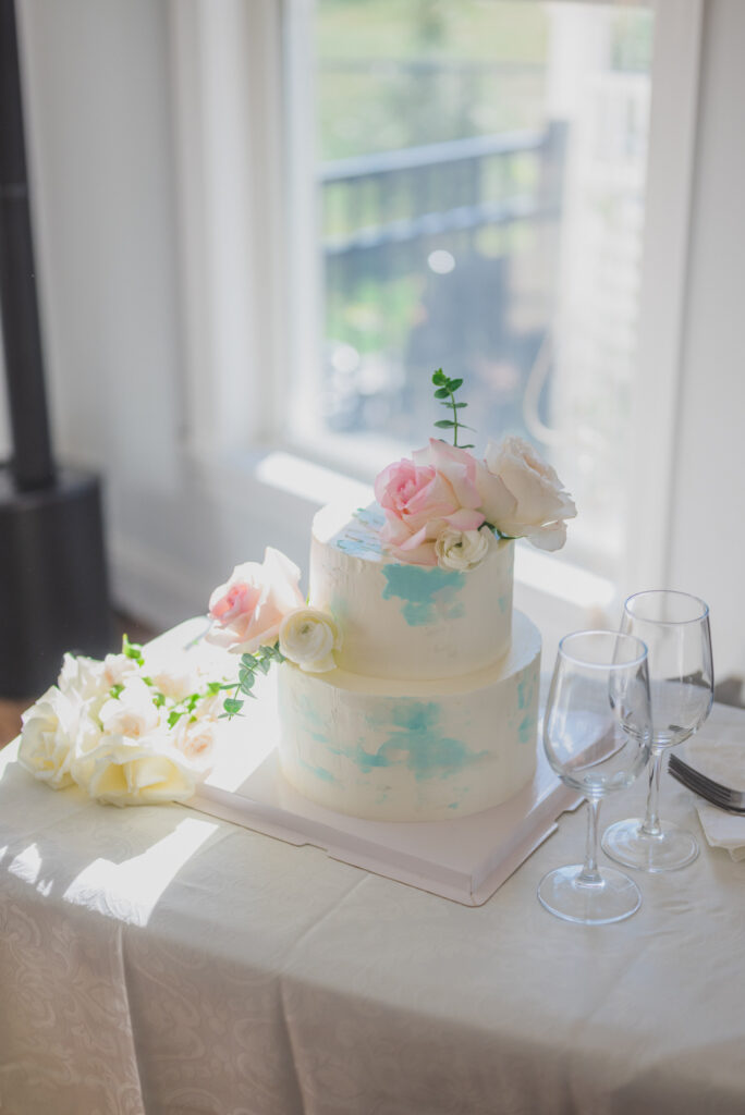 Room with rows of white chairs facing a floral arch and windows, set up for an event.